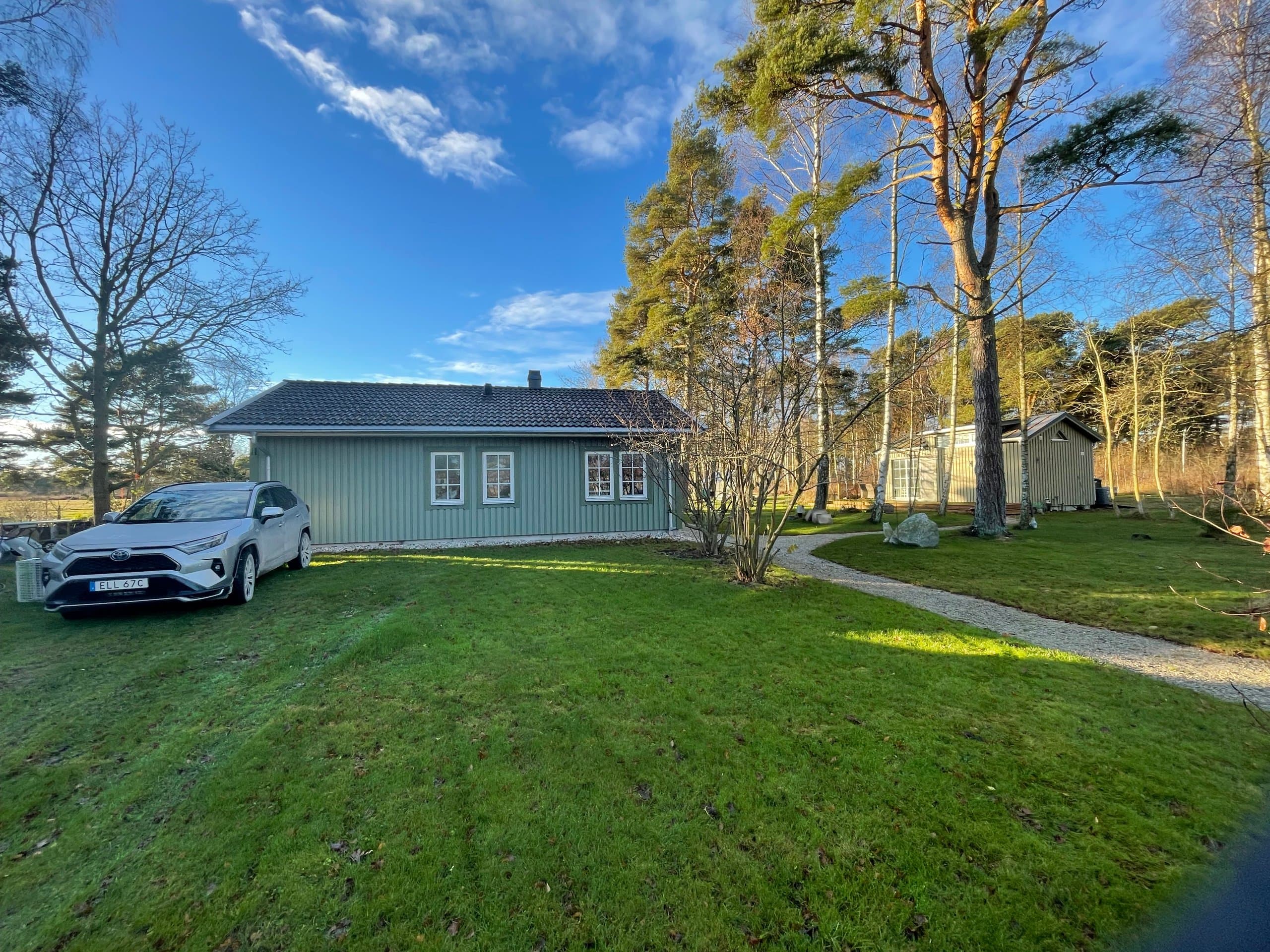 Hamngardi ligger vackert inbäddat i grönska omgiven av höga träd. Den charmiga stugan med sin gröna fasad och moderna faciliteter erbjuder den perfekta lugna retreaten nära havet och naturen.